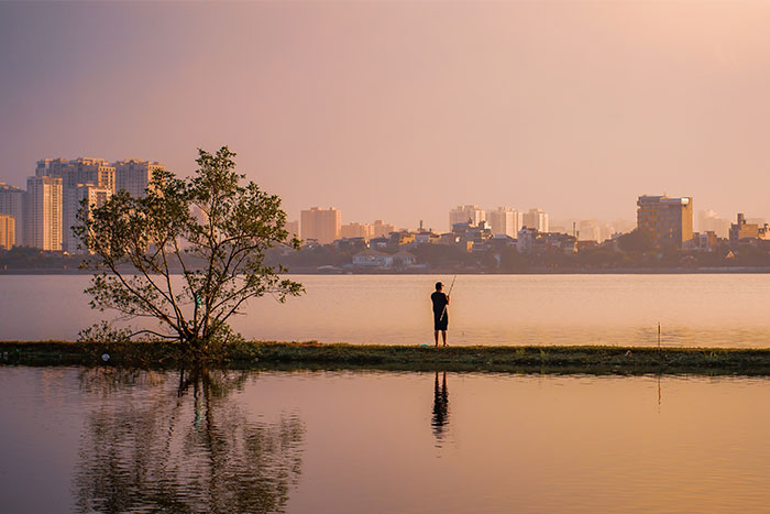 Un homme pêchant au coucher du soleil sur le lac ouest