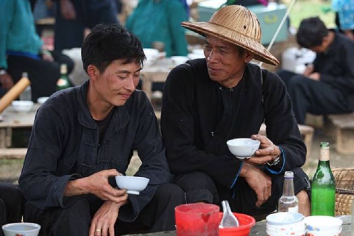 Les hommes qui boivent de l'alcool du maïs au marché de Quan Ba