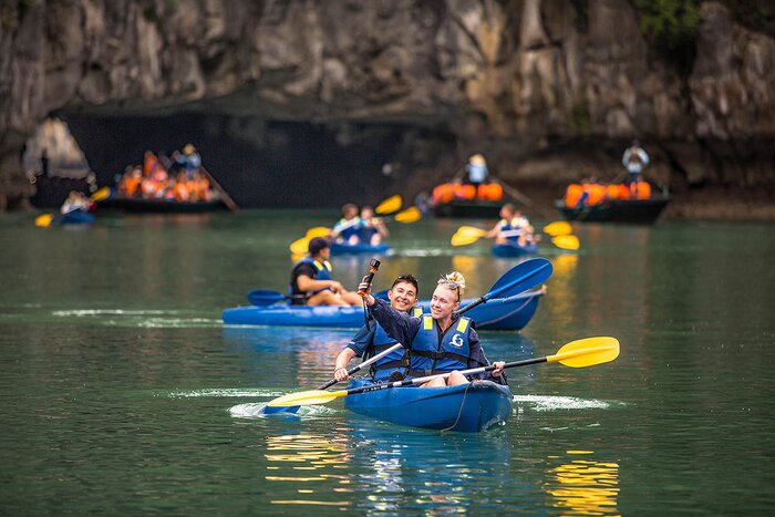 Les touristes rament des bateaux pour explorer la baie d'Ha Long