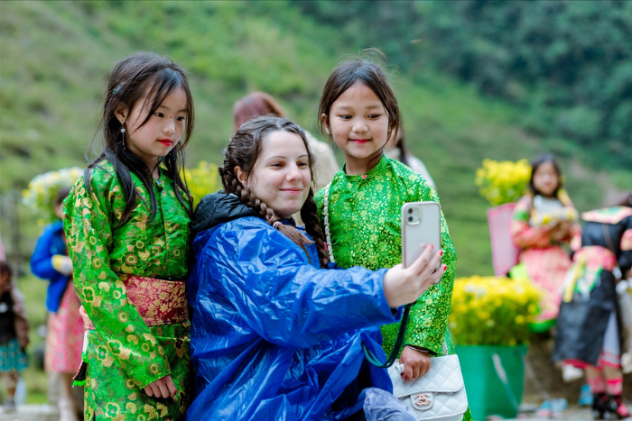 Un touriste prend des photos avec deux petites filles de minorité ethnique à Ha Giang